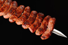 Barbecue Sausages On Skewers On Black Background.