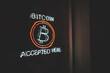 Bitcoin accepted here cryptocurrency led neon sign in a window of small business at night with copy space