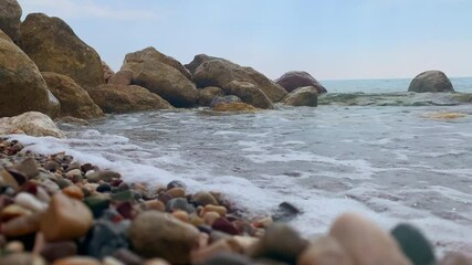 Wall Mural - rolling waves of the sea in sunlight beautiful view on blue sky sea waves washes the stones on the shore