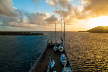 A transport ship carrying yachts stands in the bay of Martinique at sunset.