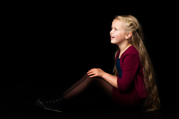 Wall Mural - Side view of happy smiling blonde girl. Isolated on black background.