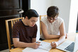 Mom helping young teenager son with online home schooling