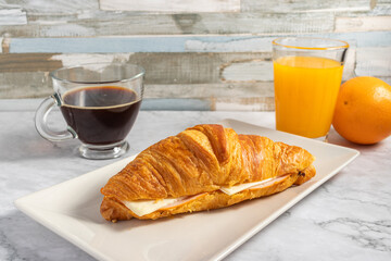 Sticker - Crunchy delicious croissant with ham and cheese filling, a cup of hot coffee and juice on a table