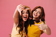 © Look! - Curly women in yellow dresses take selfie on pink background. Young modern girls in fashionable clothes and straw hats are smiling