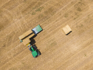 Sticker - High angle shot of green tractor loading straw bales on a trailer