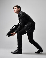 full length portrait of a brunette man wearing leather jacket and holding a science fiction gun. sta