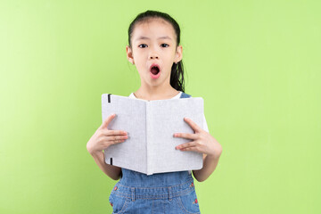 Portrait of Asian child holding book on green background