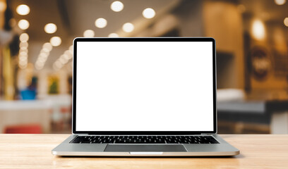 laptop blank screen on wood table with blurred coffee shop cafe interior background and lighting bok