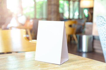 Mock up Label the blank menu frame in Bar restaurant. Stand for booklet with white sheet paper acrylic tent card on table wiht blurred background can inserting the text or picture