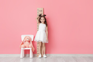 Poster - Little girl measuring height near color wall