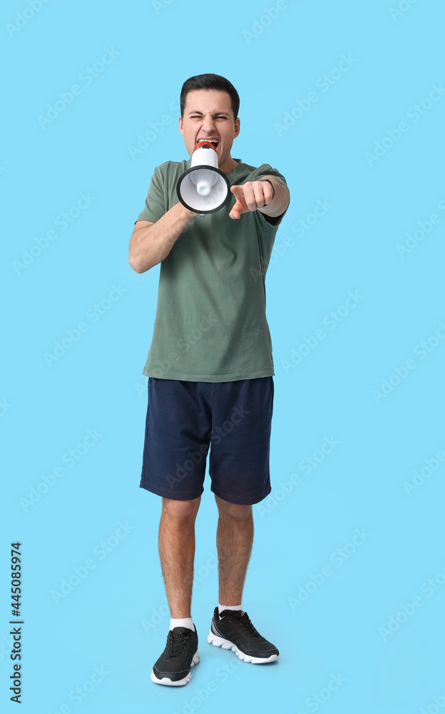 Sporty male coach with megaphone on color background