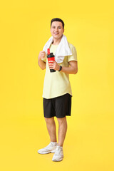 Sticker - Sporty male coach with bottle of water on color background