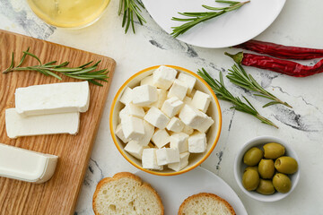 Wall Mural - Bowl with pieces of feta cheese, green olives and fresh bread on light table