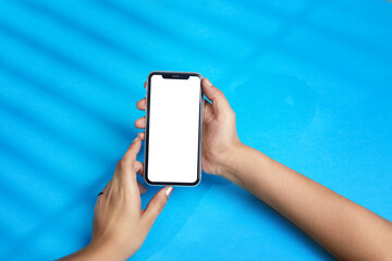 person holding mobile phone, lady using smart phone over blue background with white display for usage