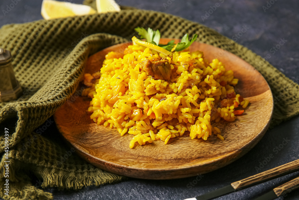 Plate with tasty pilaf on dark background
