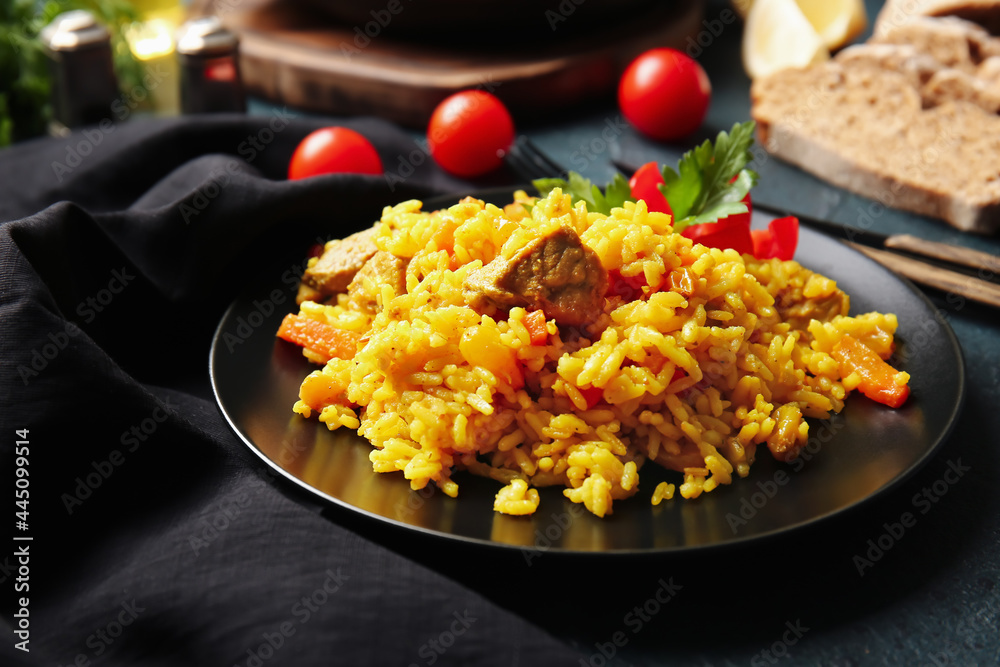Plate with tasty pilaf on dark background