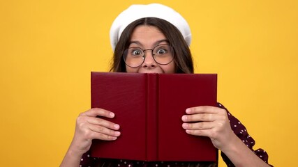 Poster - happy surprised nerd teen girl in glasses hiding behind reading book making smart face, reader