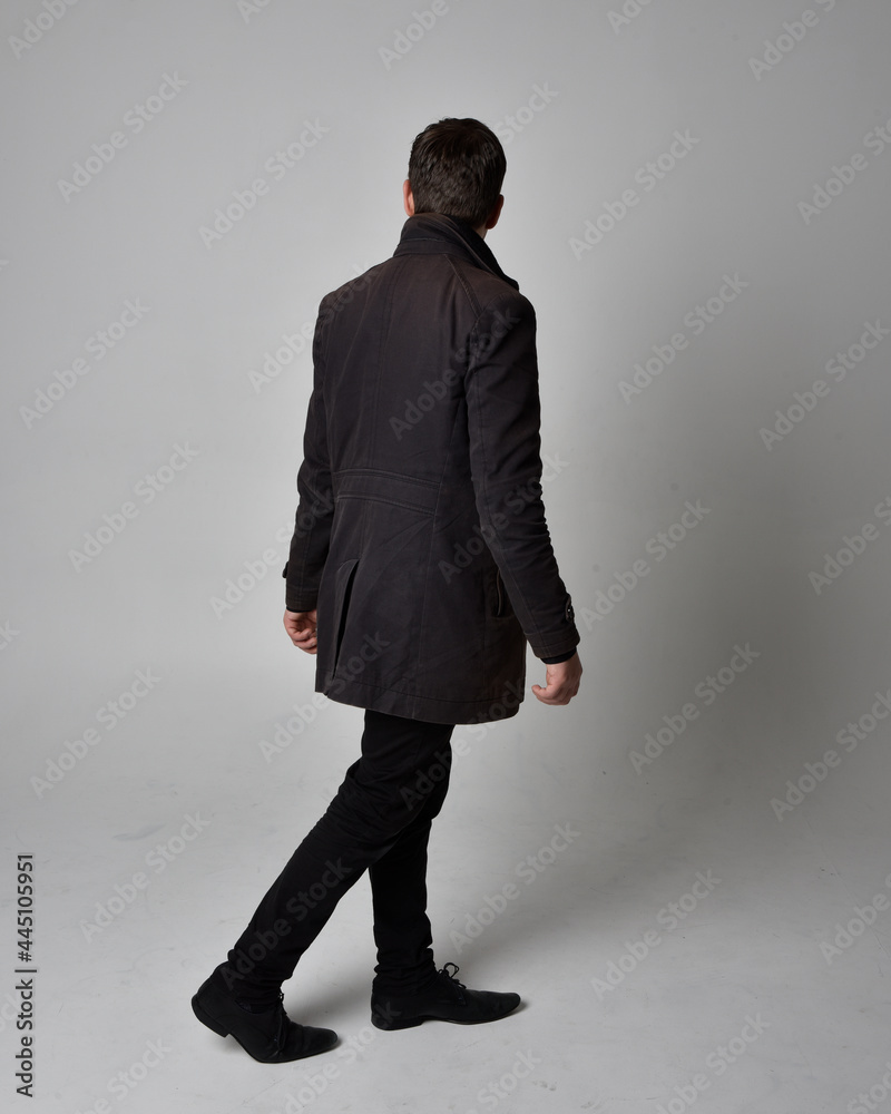 Full length portrait of a brunette man wearing black leather coat. Standing  pose facing backwards, walking away from the camera isolated against a grey  studio background. Stock Photo | Adobe Stock, image size:800x1000