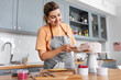 © Syda Productions - culinary, baking and cooking food concept - happy smiling young woman making layer cake and spreading topping cream on kitchen at home