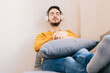 © Dani D.G - Young adult man 30s relaxed, comfortable and calm, listening to music with his wireless headphones indoors. Therapy, music and relaxation concept.