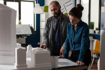 Poster - Construction architect team working at desk office on blueprint layout. Caucasian colleagues standing at maquette building model design plan to engineer construction project