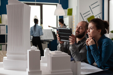 Poster - Colleagues of architectural profession work at office for digital technology with tablet. Caucasian workmates sitting at desk meeting for building model maquette construction design