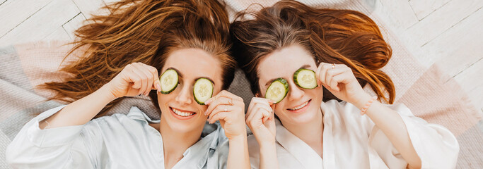 Wall Mural - two girls make homemade face and hair beauty masks. cucumbers for the freshness of the skin around t