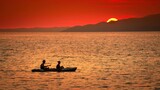 Fototapeta Fototapety do pokoju - Pływający ludzie na morzu na tle ogromnego zachodzącego słońca