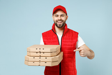 Wall Mural - Delivery guy employee man in red cap white T-shirt vest uniform workwear work dealer courier hold pizza in cardboard flatbox isolated on pastel blue color background studio portrait. Service concept