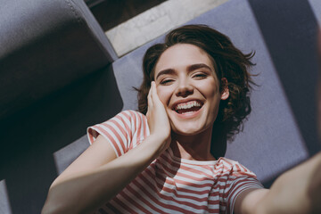 Wall Mural - Top view from above close up smiling satisfied young woman in casual clothes lying on grey sofa do selfie shot on mobile camera hold face rest indoors flat at home People lifestyle leisure concept.