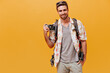 © Look! - Handsome man with ginger beard in white shirt and plaid t-shirt smiling and holding camera on isolated orange background..
