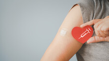 Senior Woman Holding Red Heart Shape With  Syringe And Showing Her Arm With Bandage After Got Vaccinated Or Inoculation Due To Spread Of Corona Virus, Population, Social Or Herd Immunity Concept