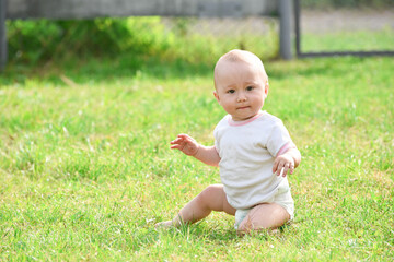 Smiling one year boy sitting in grass outdoors,summer photo