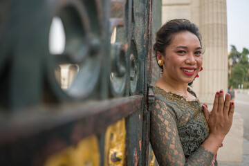 young happy Indonesian woman from Bali having vacation in Europe - attractive and cheerful Balinese tourist girl in traditional outfit touring in the city enjoying holidays trip