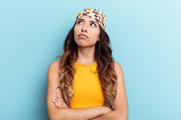 Young mexican woman isolated on blue background tired of a repetitive task.