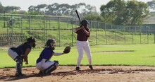 Diverse Group Of Female Baseball Players Playing On The Field, Hitter Swinging For Pitched Ball