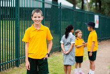 Portrait Of Happy Aussie School Boy Near School Fence
