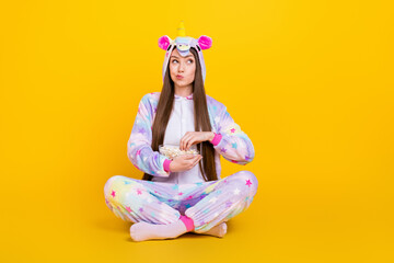 Canvas Print - Portrait of attractive minded suspicious girl sitting lotus pose eating corn thinking isolated over bright yellow color background