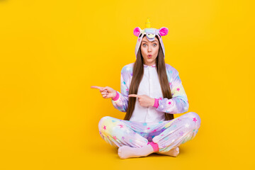 Canvas Print - Portrait of attractive cheerful amazed girl wearing kingurumi showing copy space isolated over bright yellow color background