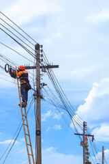 Low angle view of technician on wooden ladder checking fiber optic cables in internet splitter box on electric pole against white cloudy in vertical frame