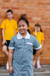 © Austockphoto - School girl in green and white check public school dress outside classroom