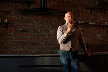 Wall Mural - handsome man looking at the red wine in his glass .