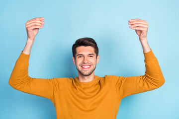 Sticker - Photo of pretty charming young guy dressed yellow pullover holding arms empty space smiling isolated blue color background