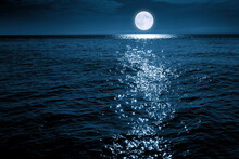 This Large Full Blue Moon Rises Brightly Over The Calm Ocean Creating Sparkles Across The Waves