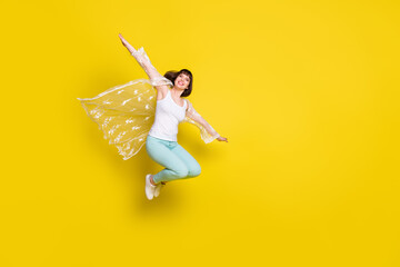 Wall Mural - Full body photo of attractive young cheerful woman jump up plane wings hands isolated on yellow color background