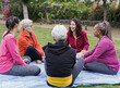 Multiracial women sitting and talking at city park - Multi generational people having fun together