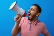 © fotofabrika - Young arab man with megaphone proclaiming something isolated on blue background