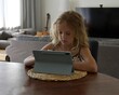 Young girl draws on tablet at home. Child using gadget. Kid watching tablet.