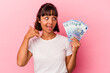 © Asier - Young mixed race woman holding bills isolated on pink background showing a mobile phone call gesture with fingers.