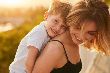 happy mother carrying little son in summer day